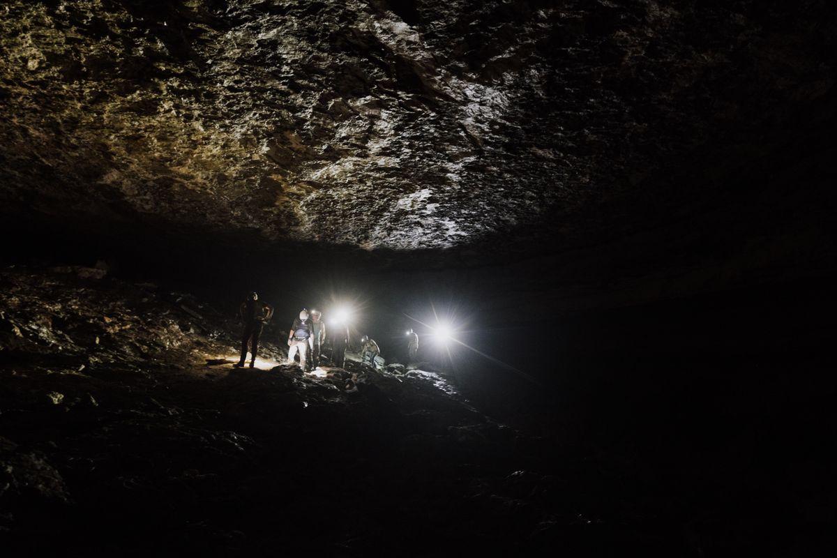 Equipo de espeleólogos con linternas frontales explorando una cueva profunda
