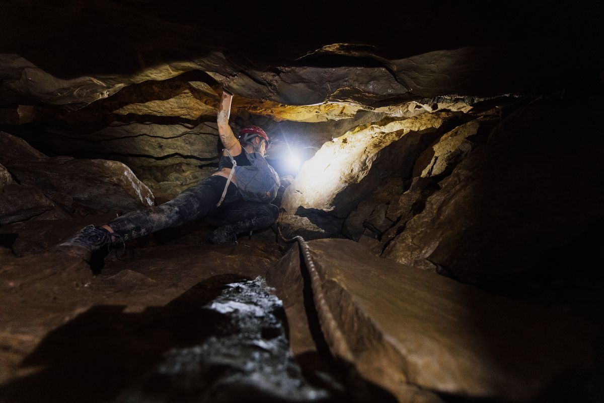 Espeleólogo con frontal explorando formaciones rocosas en una cueva