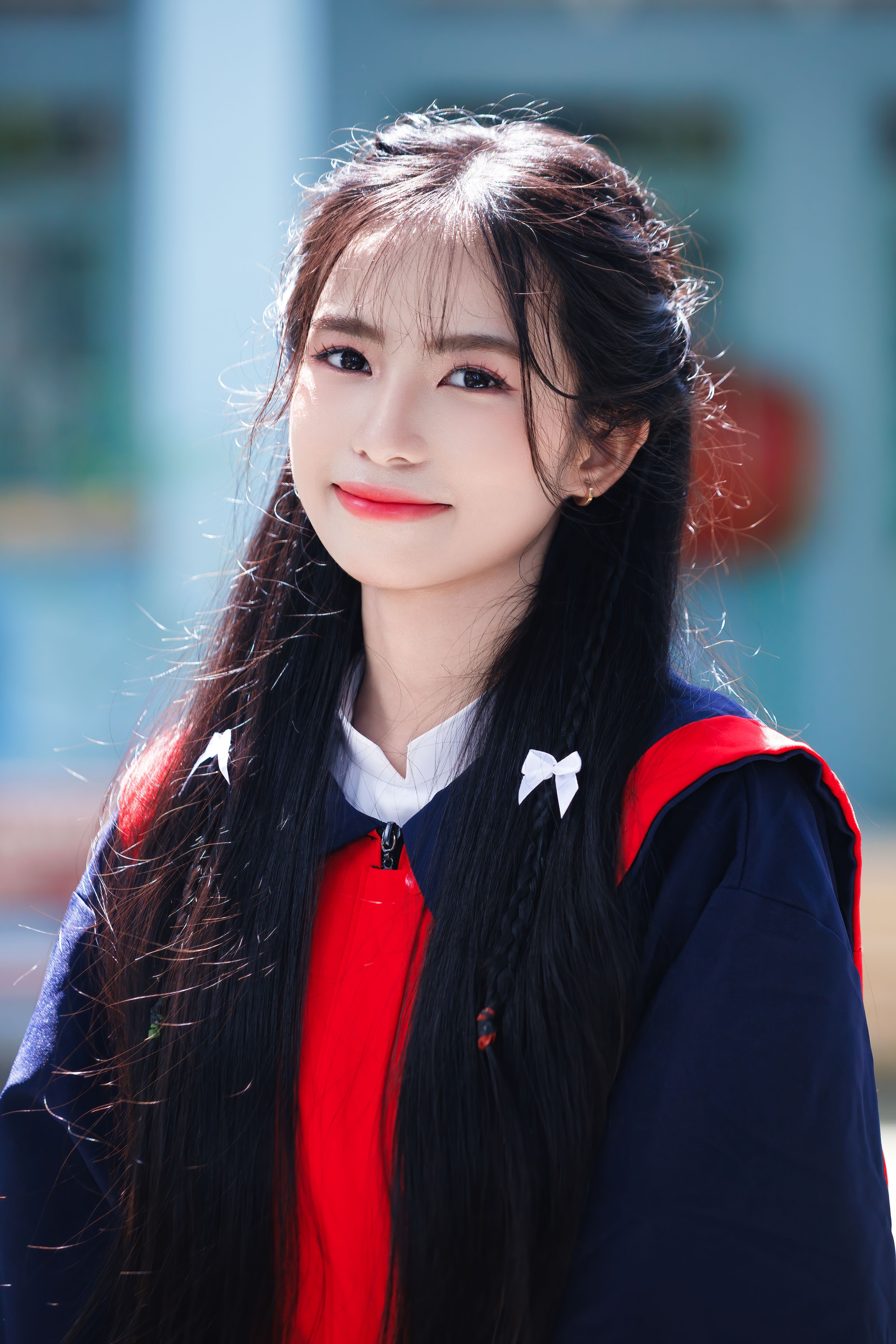 Portrait of a young woman with long hair smiling outdoors in bright sunlight.
