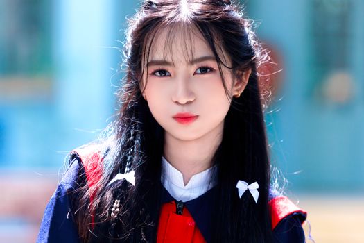 Close-up of a young woman in a school uniform, captured outdoors in natural light.