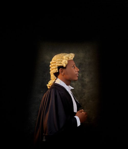 Free Side profile of a lawyer wearing a traditional wig and gown, isolated on a dark background. Stock Photo