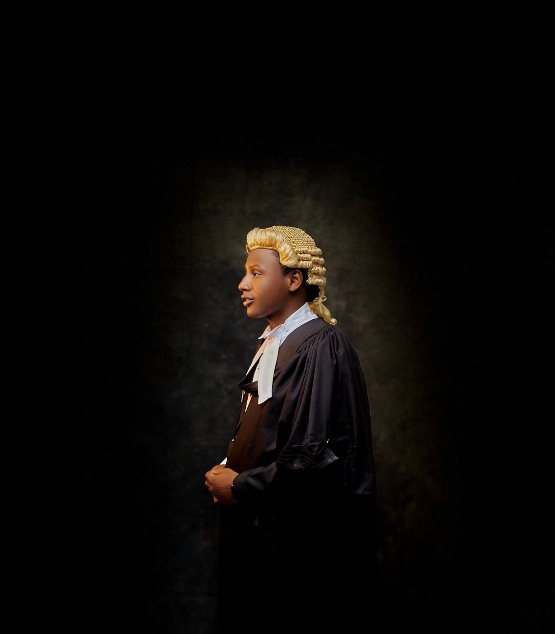 Profiel van een advocaat die een traditionele pruik en toga draagt, van opzij gezien tegen een donkere achtergrond.