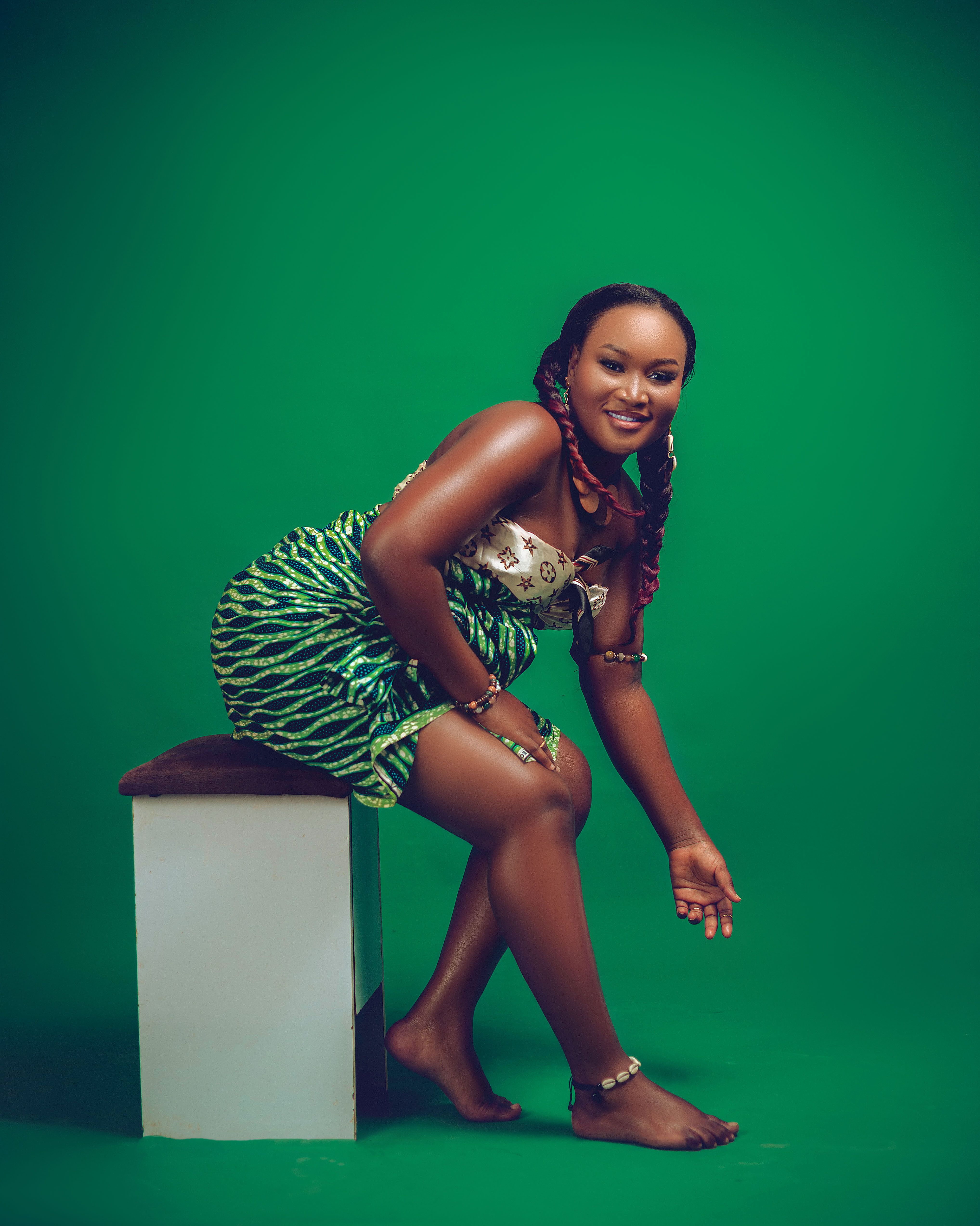 Woman in vibrant green dress sitting against a matching green background.