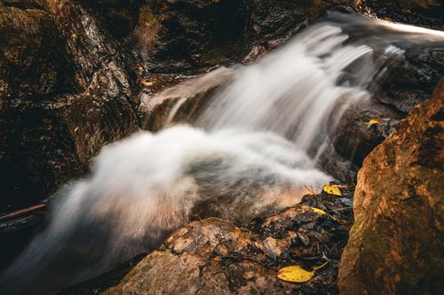 Free Captivating waterfall flowing through rocky terrain in a lush forest. Perfect for nature lovers. Stock Photo