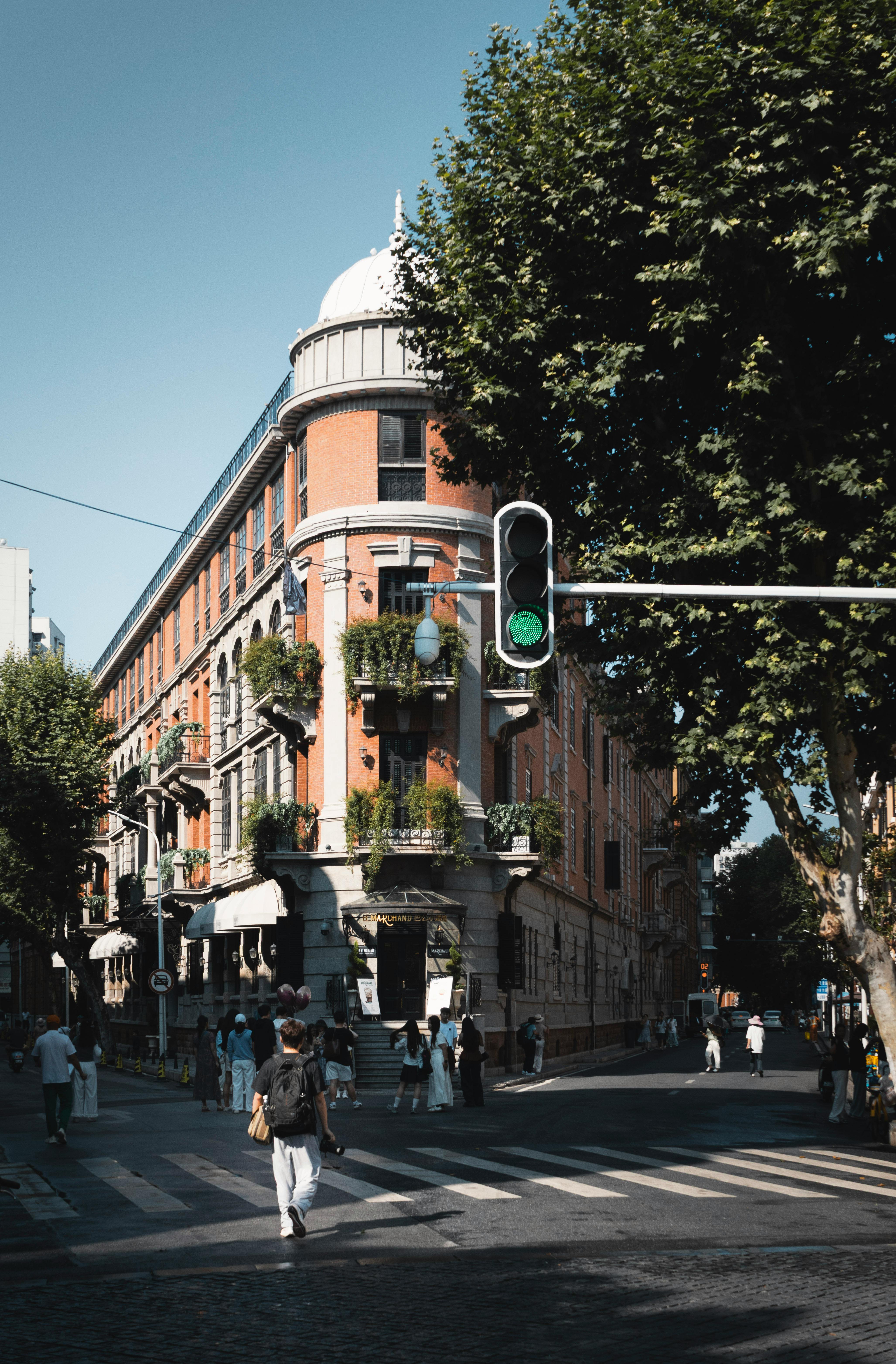 Charming European-style building with ornate facade at a busy street corner on a sunny day.