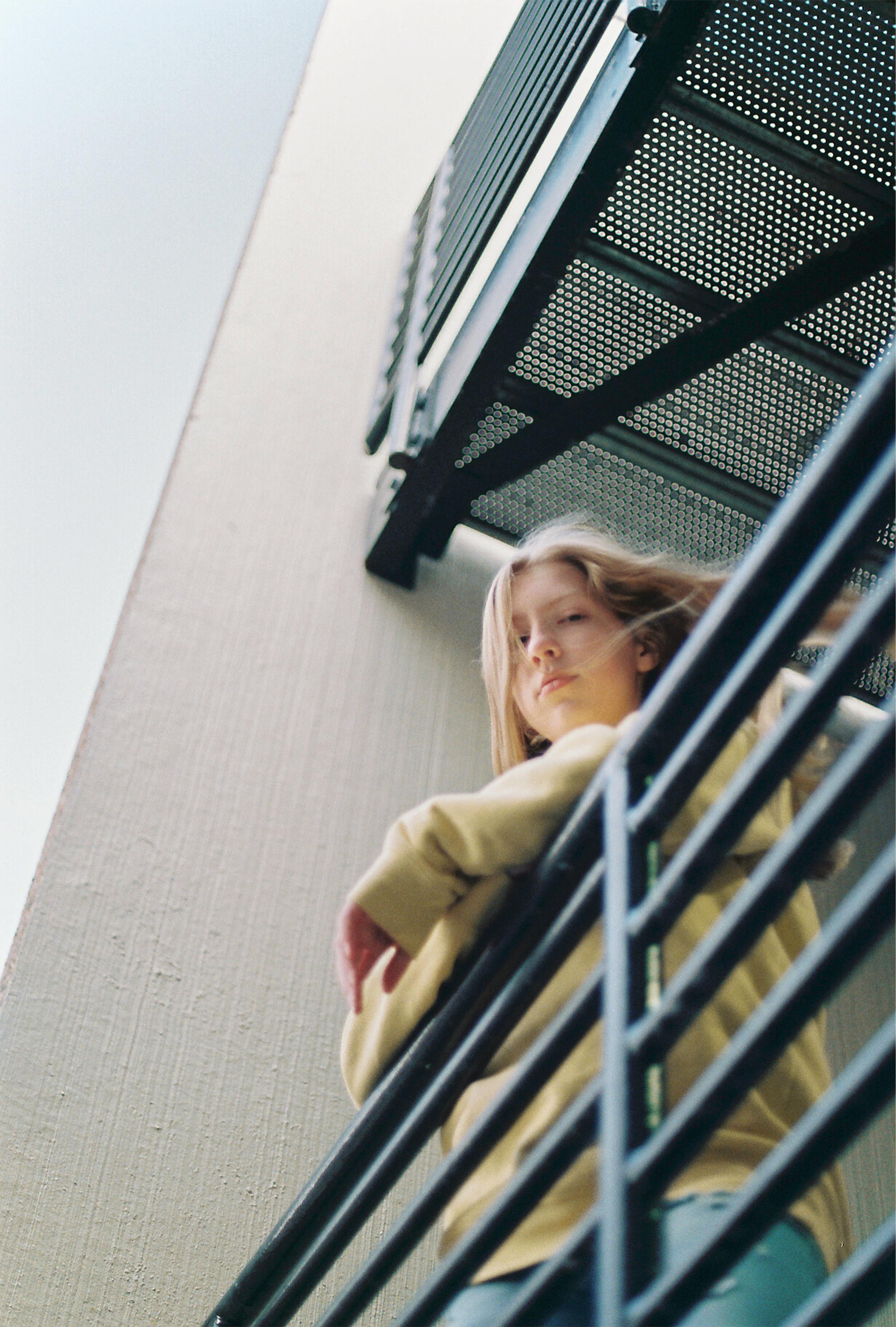 woman wearing yellow sweater leaning on railing