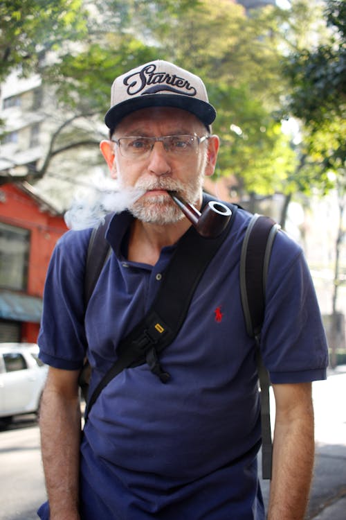 Homem De Camisa Polo Azul Fumando Ao Ar Livre