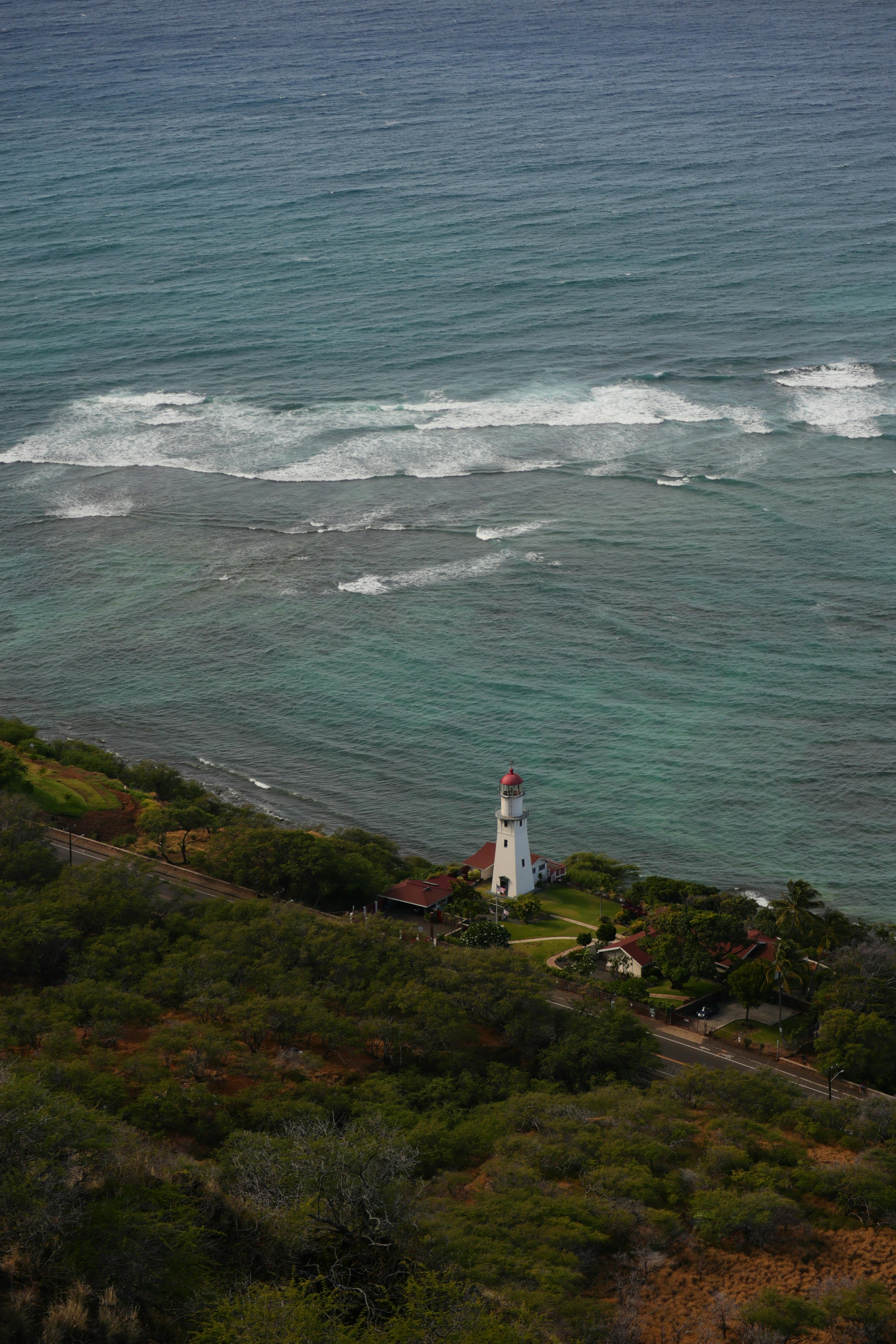 A stunning aerial view of Diamond Head Lighthouse, Hawaii, surrounded by ocean waves.