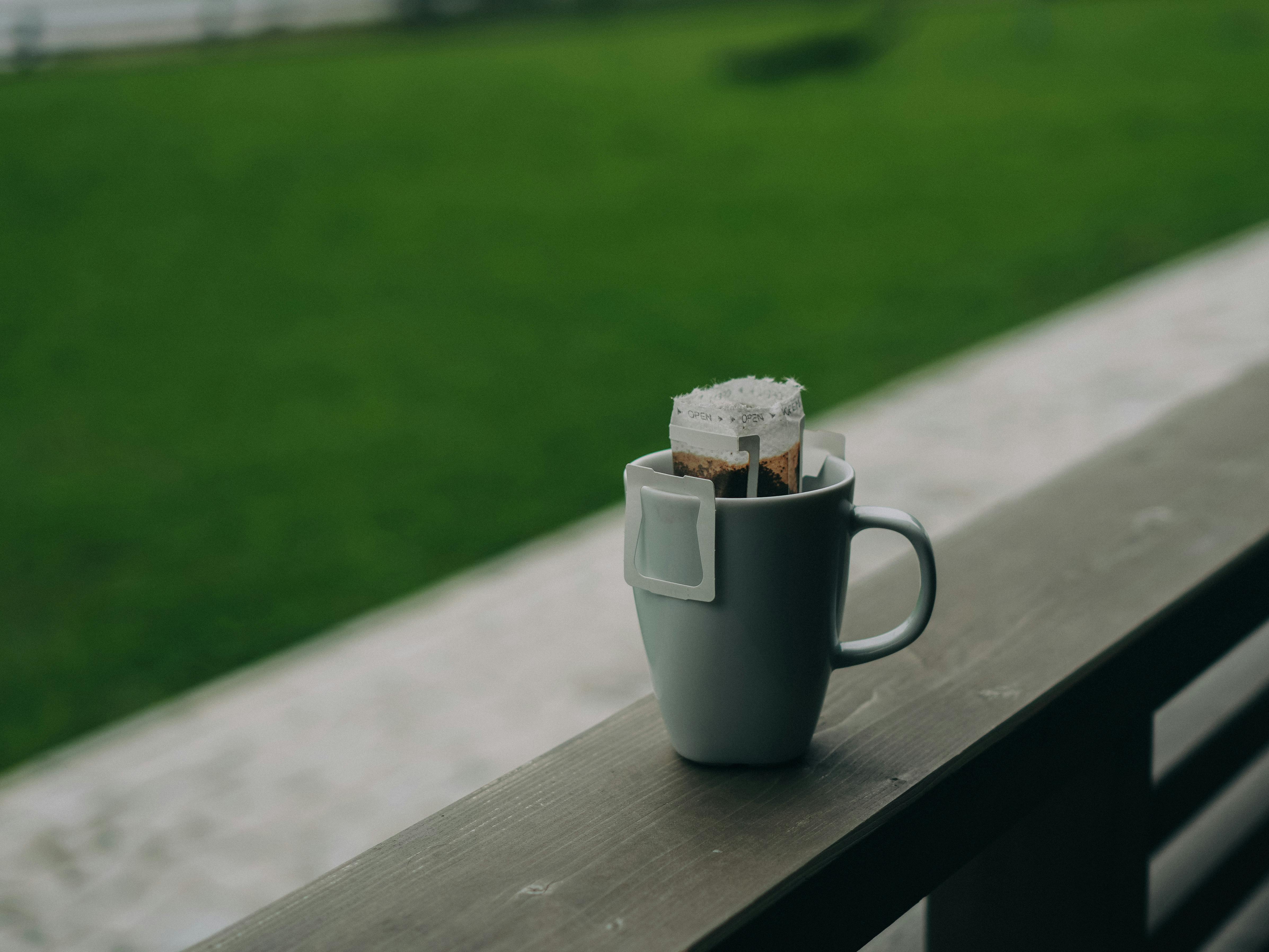 Single-serve drip coffee bag brewing over a ceramic mug