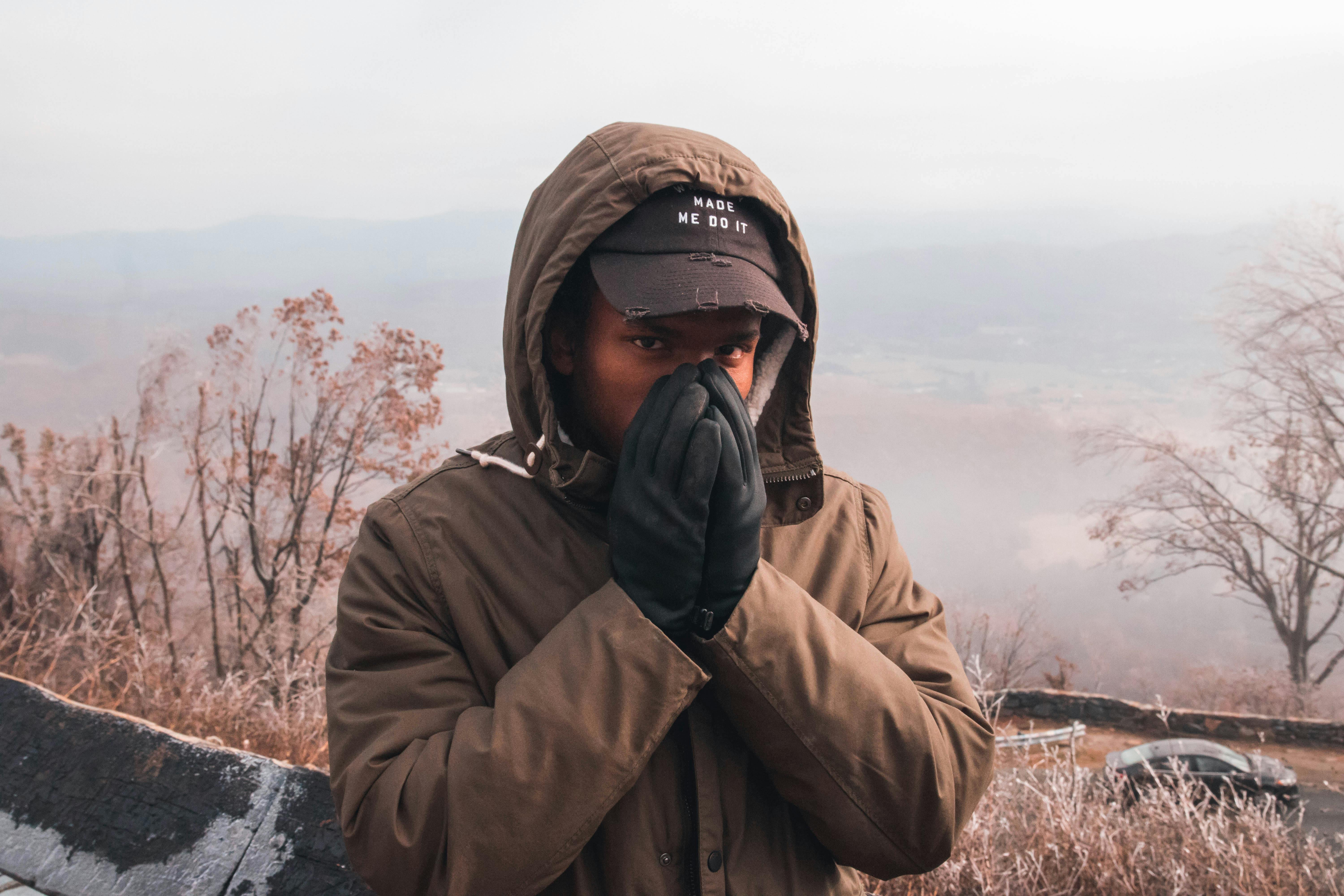 一名戴着帽子、身穿冬装的男子在户外摆出姿势，展现寒冷天气的时尚