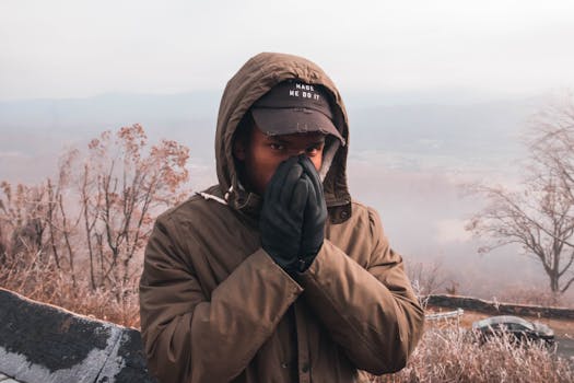 一名戴着帽子、身穿冬装的男子在户外摆出姿势，展现寒冷天气的时尚