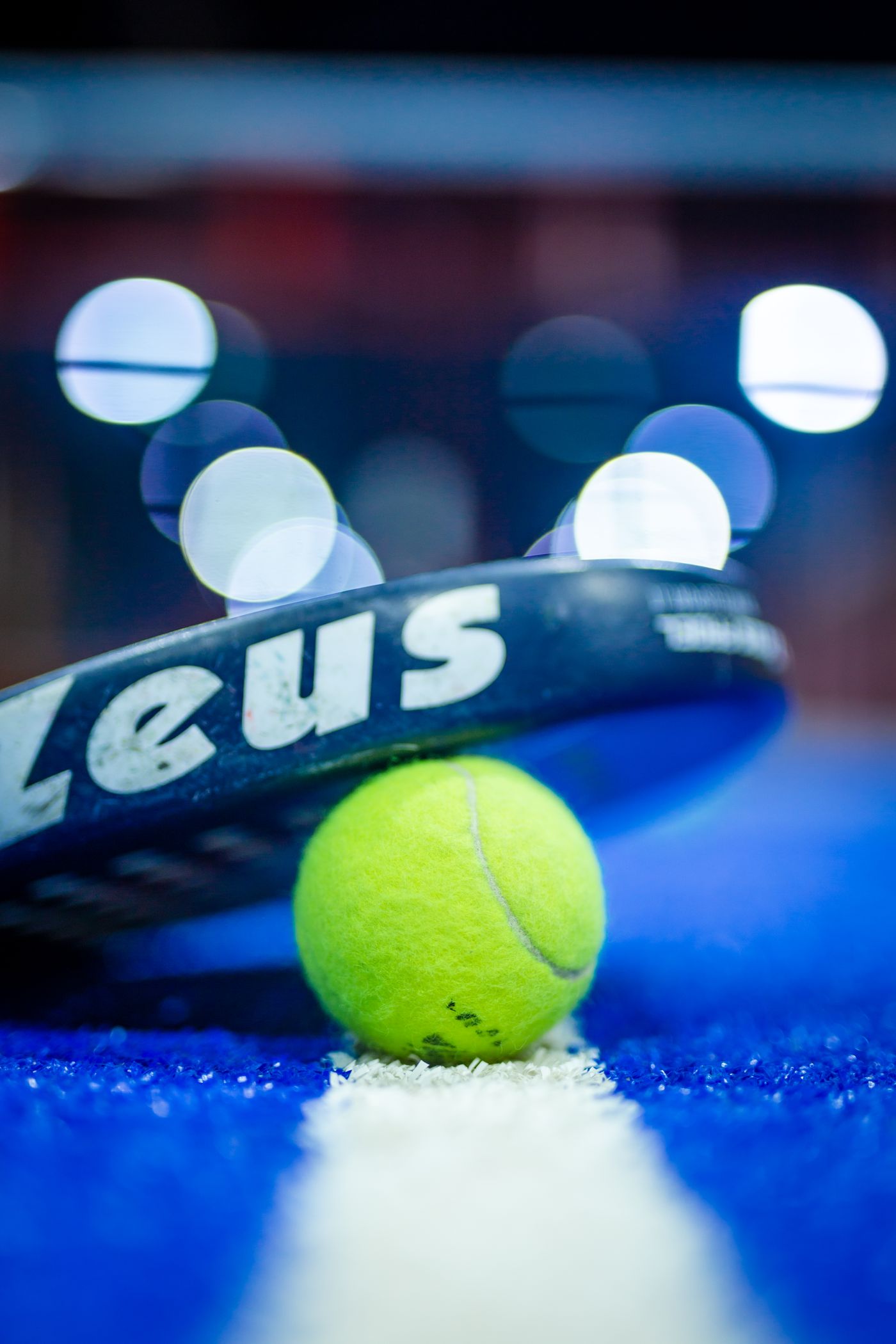 Raquete e bola de padel em quadra azul