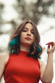 户外环境中，一位头发鲜艳、身着红色衬衫的女子特写肖像，展现时尚现代的外观