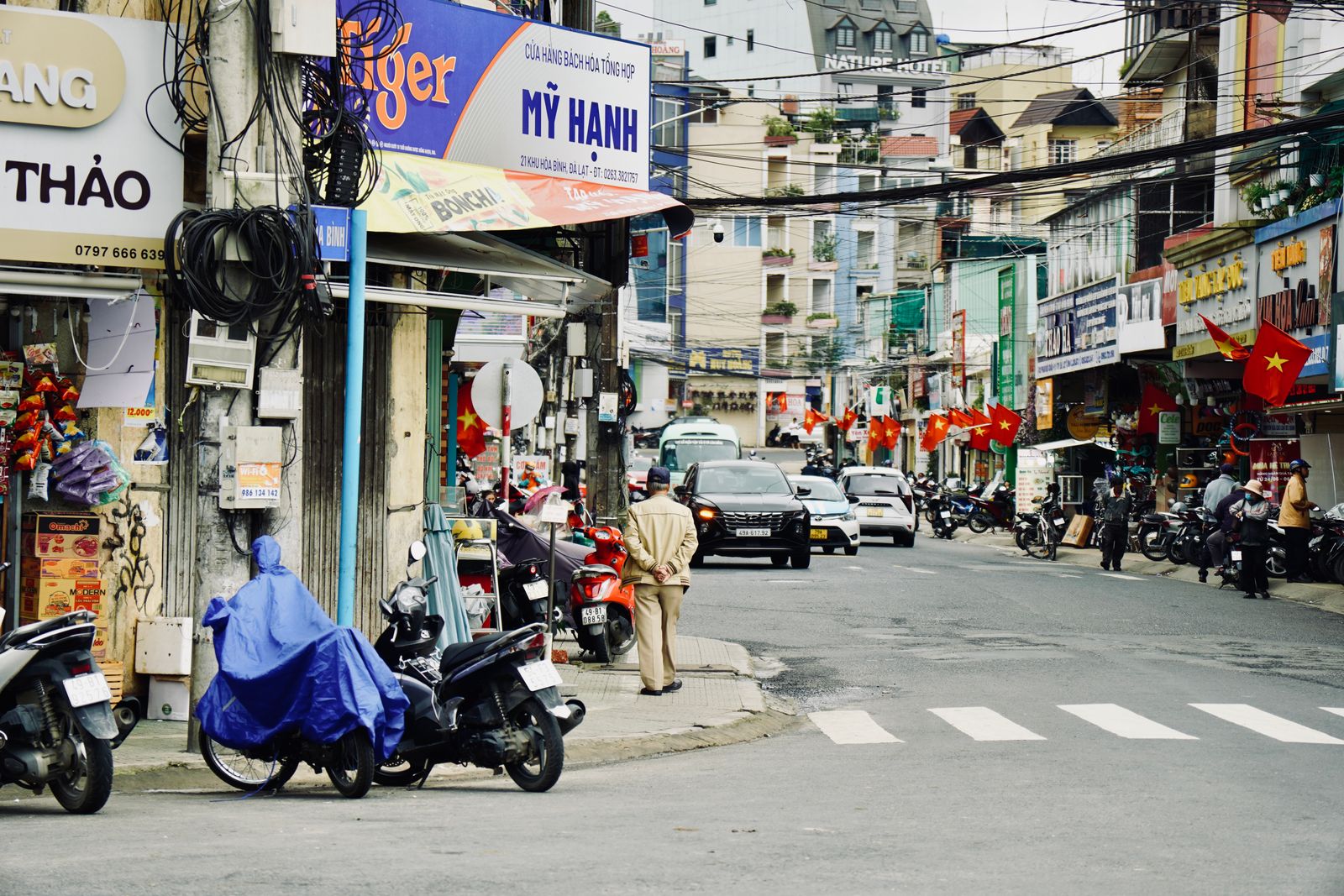 Busy street scene in Vietnam with motorbikes, shops, and pedestrians, showcasing vibrant urban life.