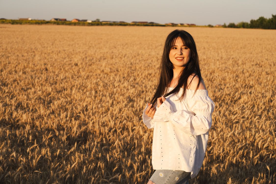 Woman Smiling in Wheat Field at Sunset · Free Stock Photo