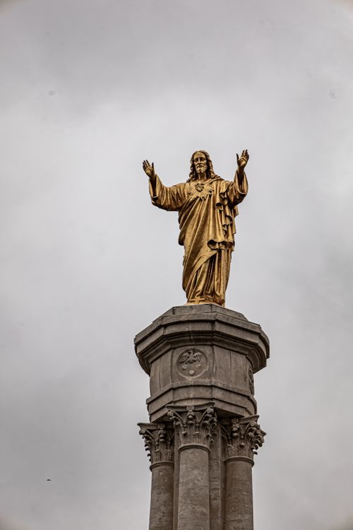 Free Majestic golden statue of Christ on a column in Fátima, Portugal under overcast skies. Stock Photo