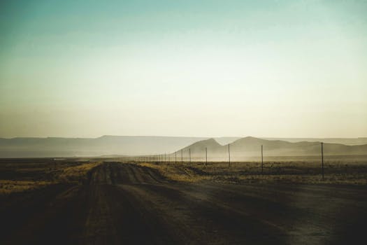 A tranquil desert road stretches into the horizon at sunrise, capturing the vastness and solitude of nature.