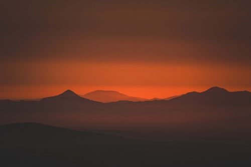 Free Captivating silhouette of mountains at sunset with vibrant orange hues. Stock Photo