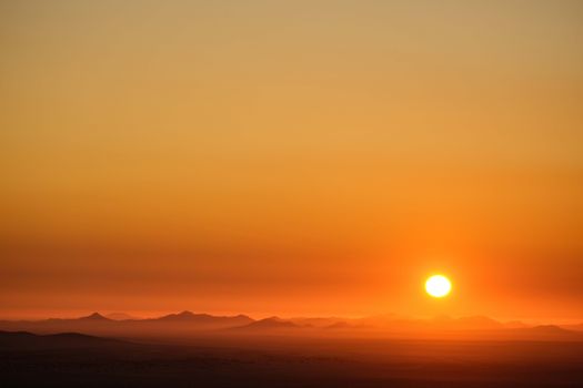 Captivating sunset over vast desert dunes, evoking tranquility with warm, golden hues.