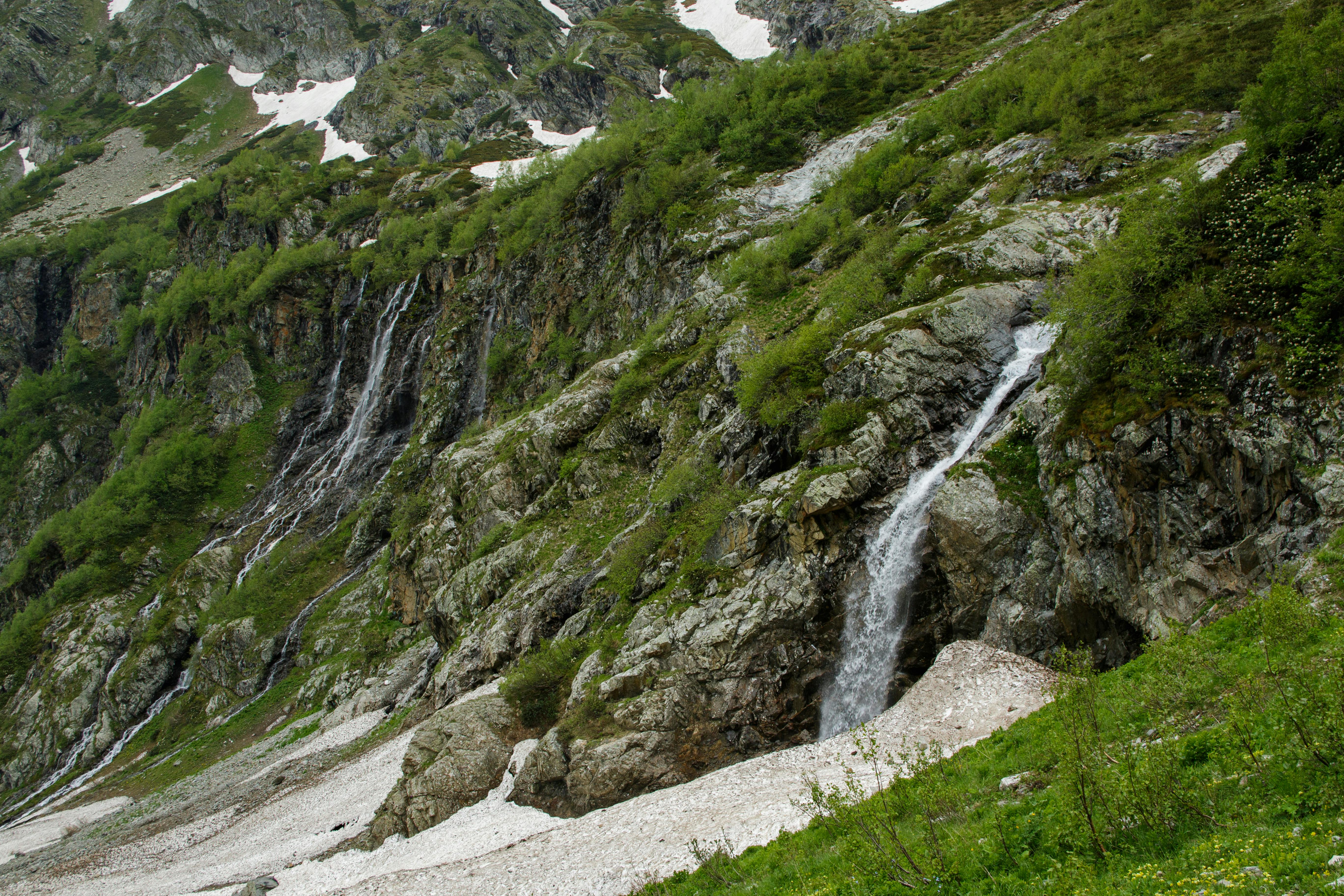 Ücretsiz Kafkas Dağları'nda yemyeşil doğa ve kayalık araziyle çevrili, çağlayan bir şelalenin muhteşem manzarası. Stok Fotoğraflar
