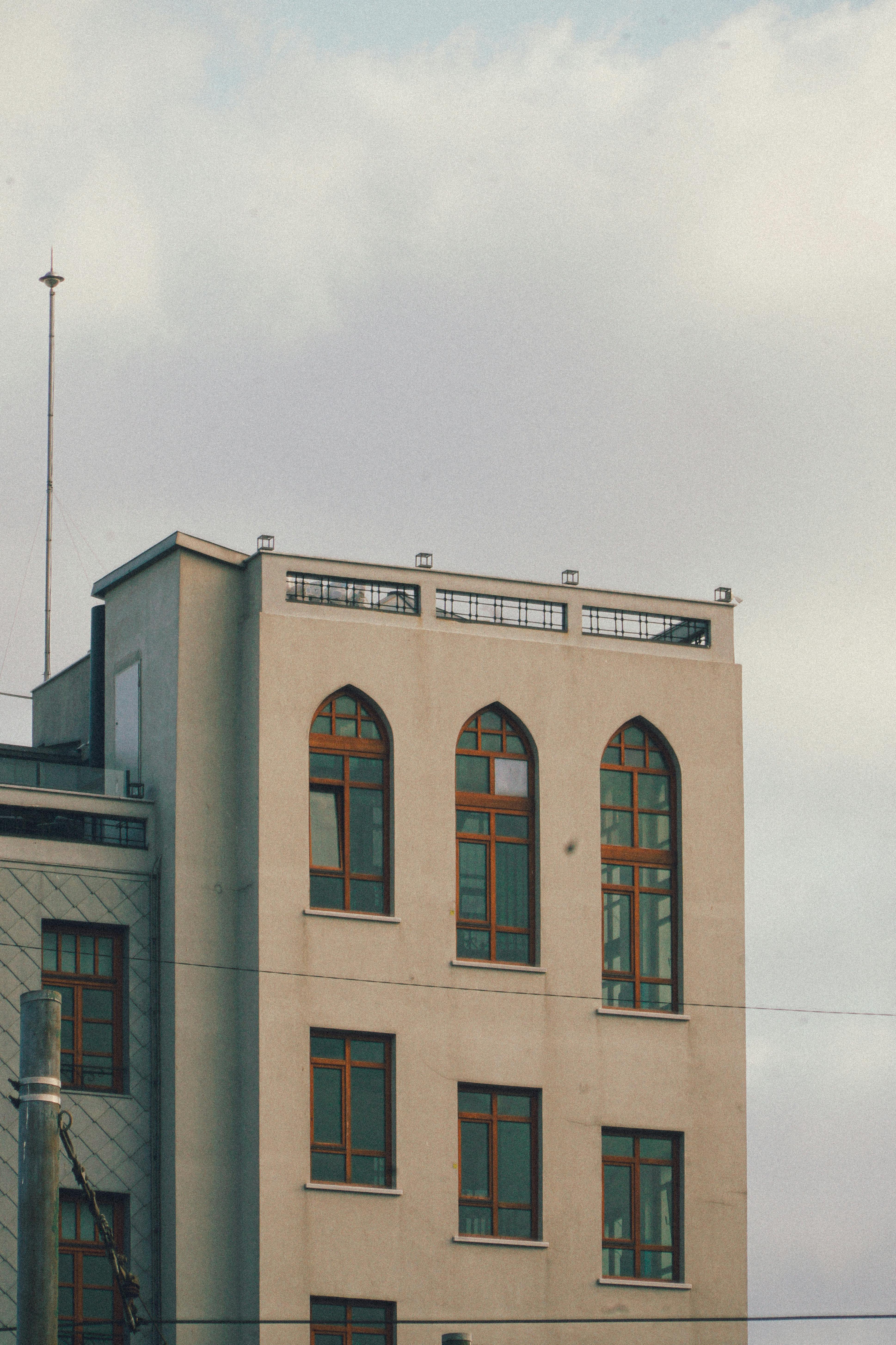 Gratis En minimalistisk, moderne bygningsfacade med store vinduer og en neutral tone, fanget i løbet af dagen. Lagerfoto