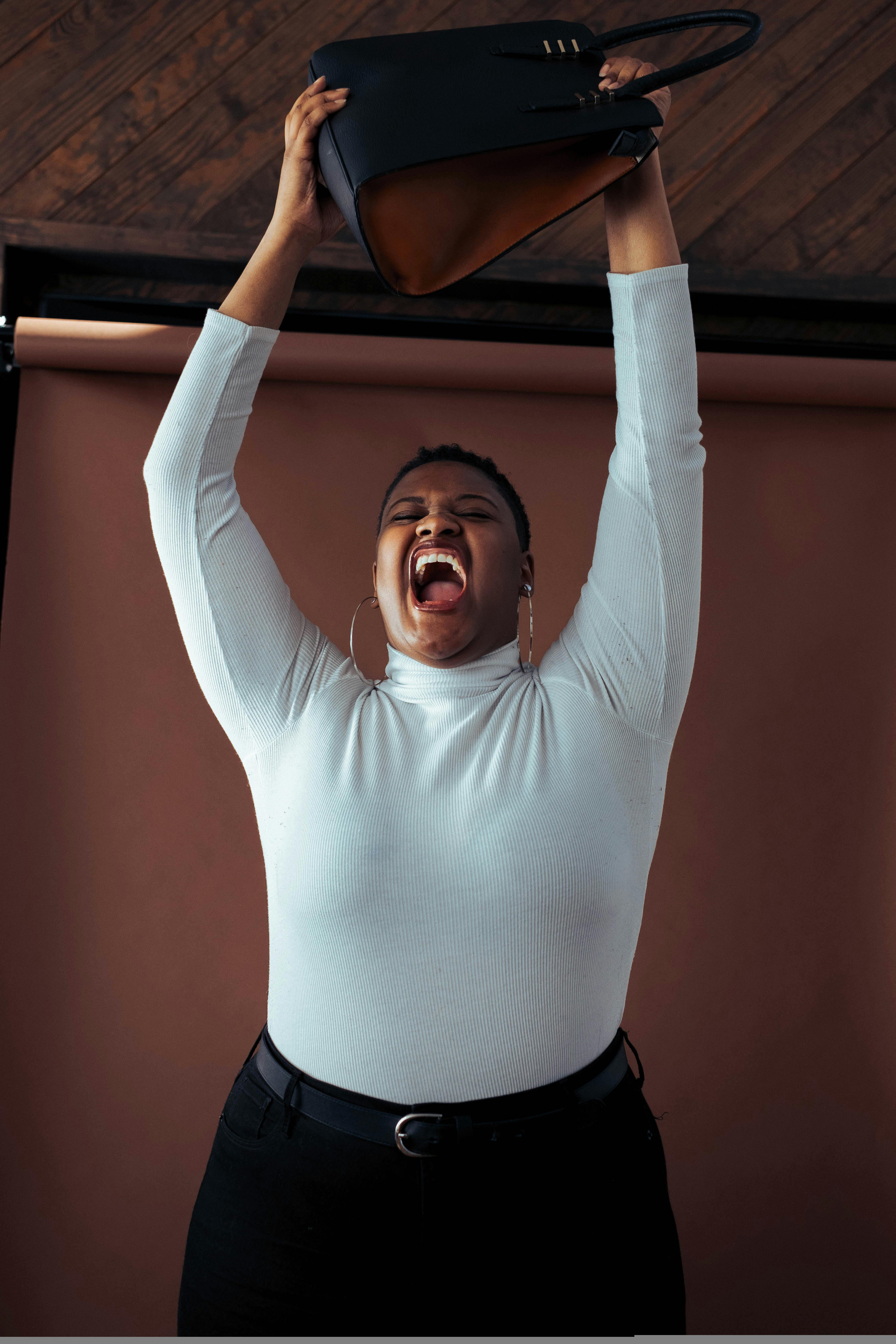 这幅肖像画描绘了一名妇女在室内举起双臂庆祝的场面，极具感染力