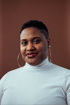 一位短发、戴着圆环耳环的女士在工作室里自信地摆着姿势