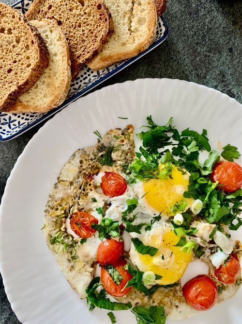 Free A vibrant breakfast plate featuring sunny side up eggs with herbs, cherry tomatoes, and toast. Stock Photo