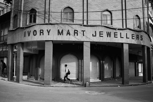 Monochrome photo of a person walking past Ivory Mart Jewellers in Delhi, India.