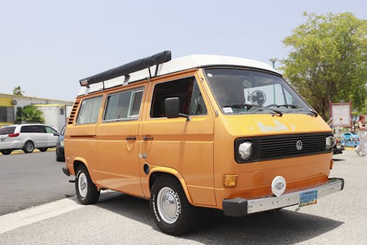 A classic orange Volkswagen van captured on a sunny day in a parking lot.