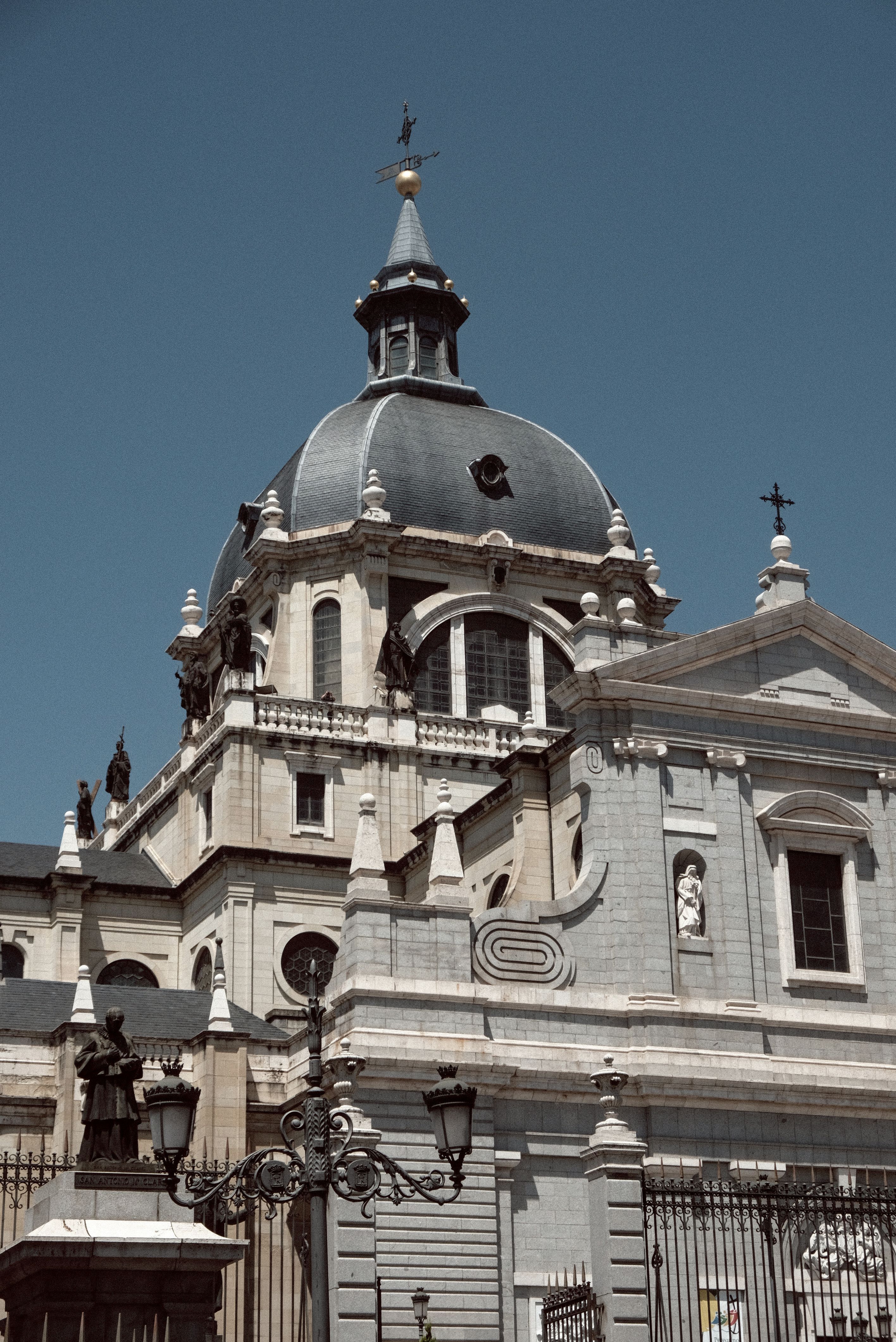 Stunning architectural details of Almudena Cathedral under a clear blue sky in Madrid, Spain.