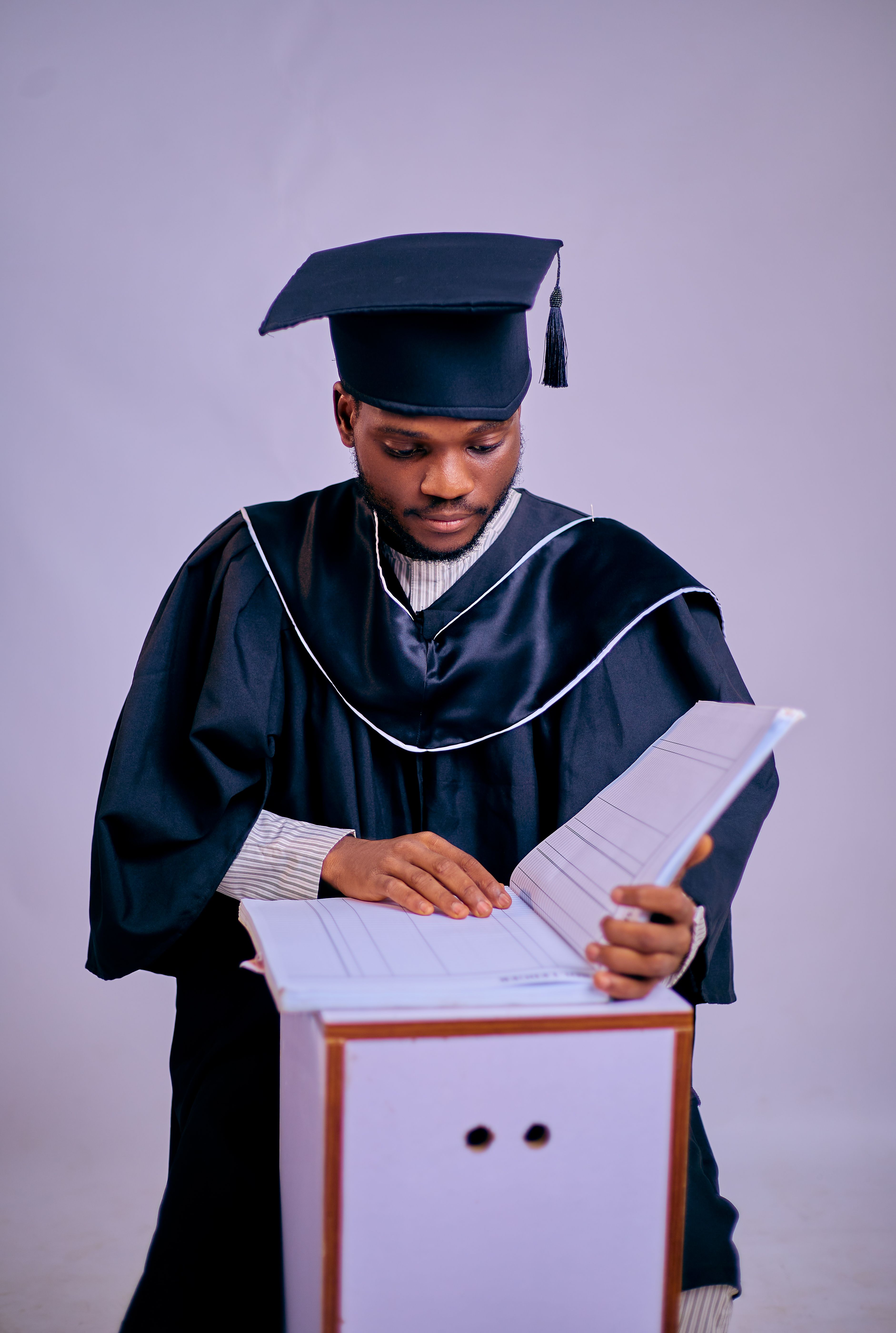Young Graduate Reviewing Diploma in Studio Setting · Free Stock Photo