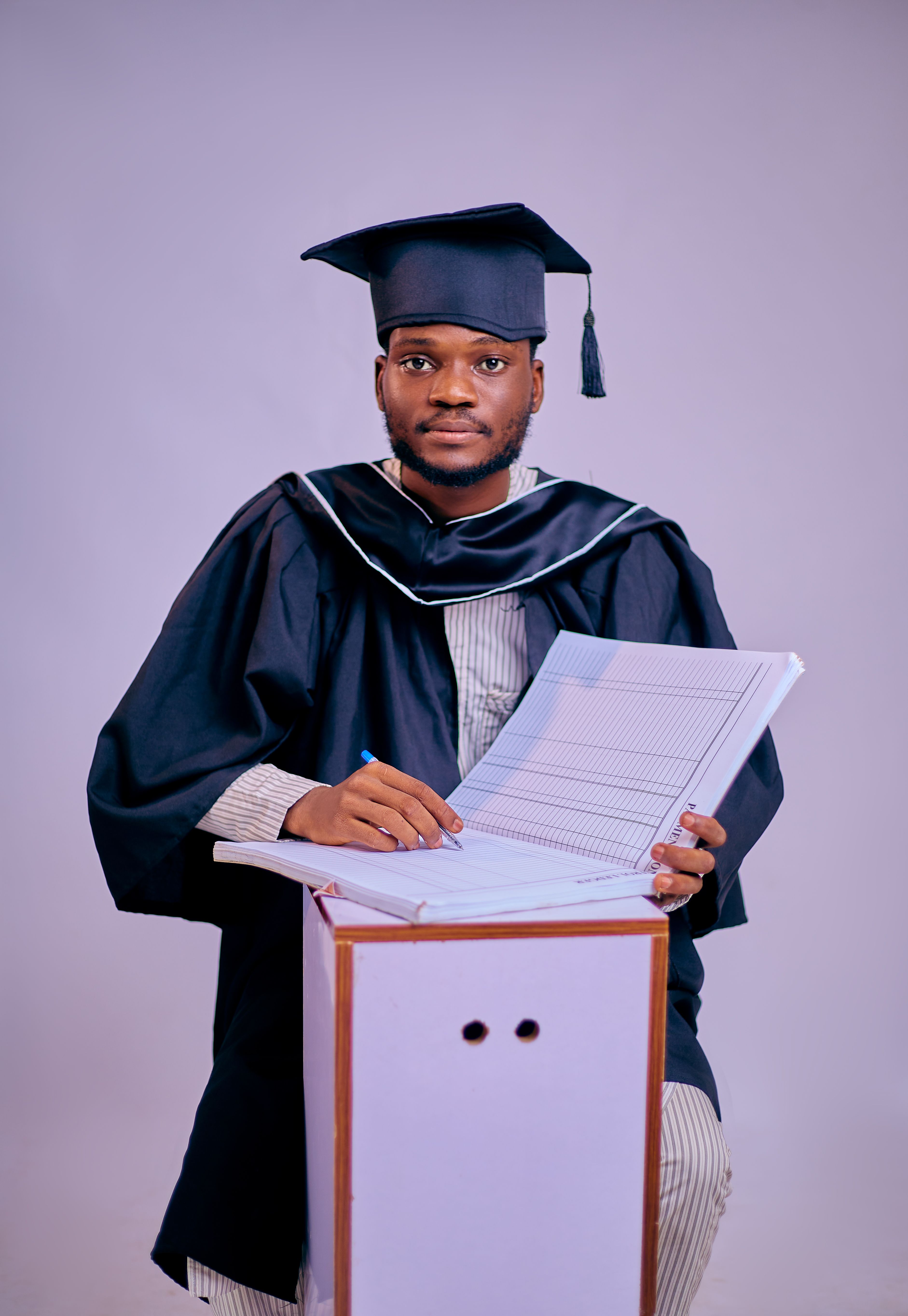 African male graduate in cap and gown holding diploma, ready for the next step.