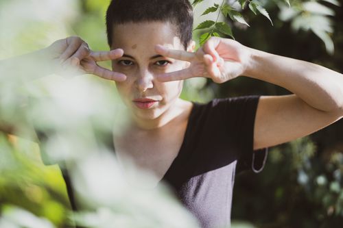Free A young woman poses outdoors with a playful hand gesture in natural light. Stock Photo