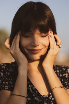 Portrait of a woman with short hair enjoying a serene moment outdoors, eyes closed, in warm sunlight.