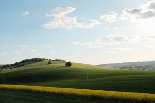 Free Scenic view of green rolling hills under a bright blue sky with clouds. Stock Photo