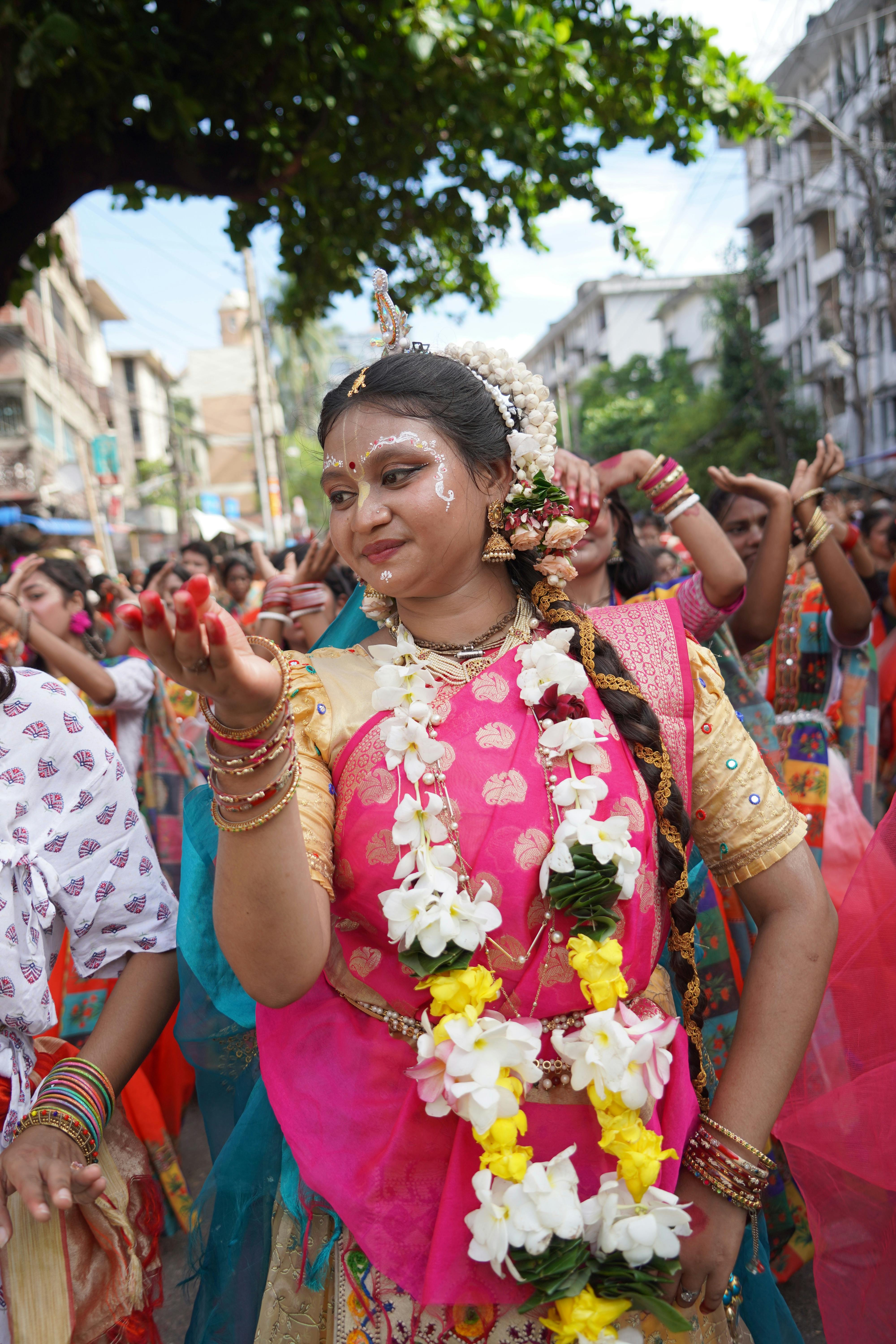 Woman in vibrant traditional attire dances in a festive street parade.