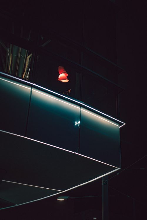 Free Elegant night view of modern architecture featuring illuminated red lamp and reflections. Stock Photo