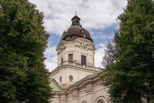 Free Captivating view of a historic church tower in Stockholm framed by lush trees and a blue sky. Stock Photo