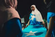 Young person holding the Somalia flag during a night celebration in Mogadishu. Patriotic spirit in Banaadir region.