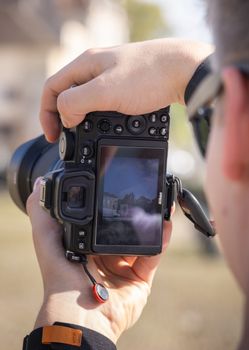Photographer focuses on capturing an outdoor scene using a professional DSLR camera.