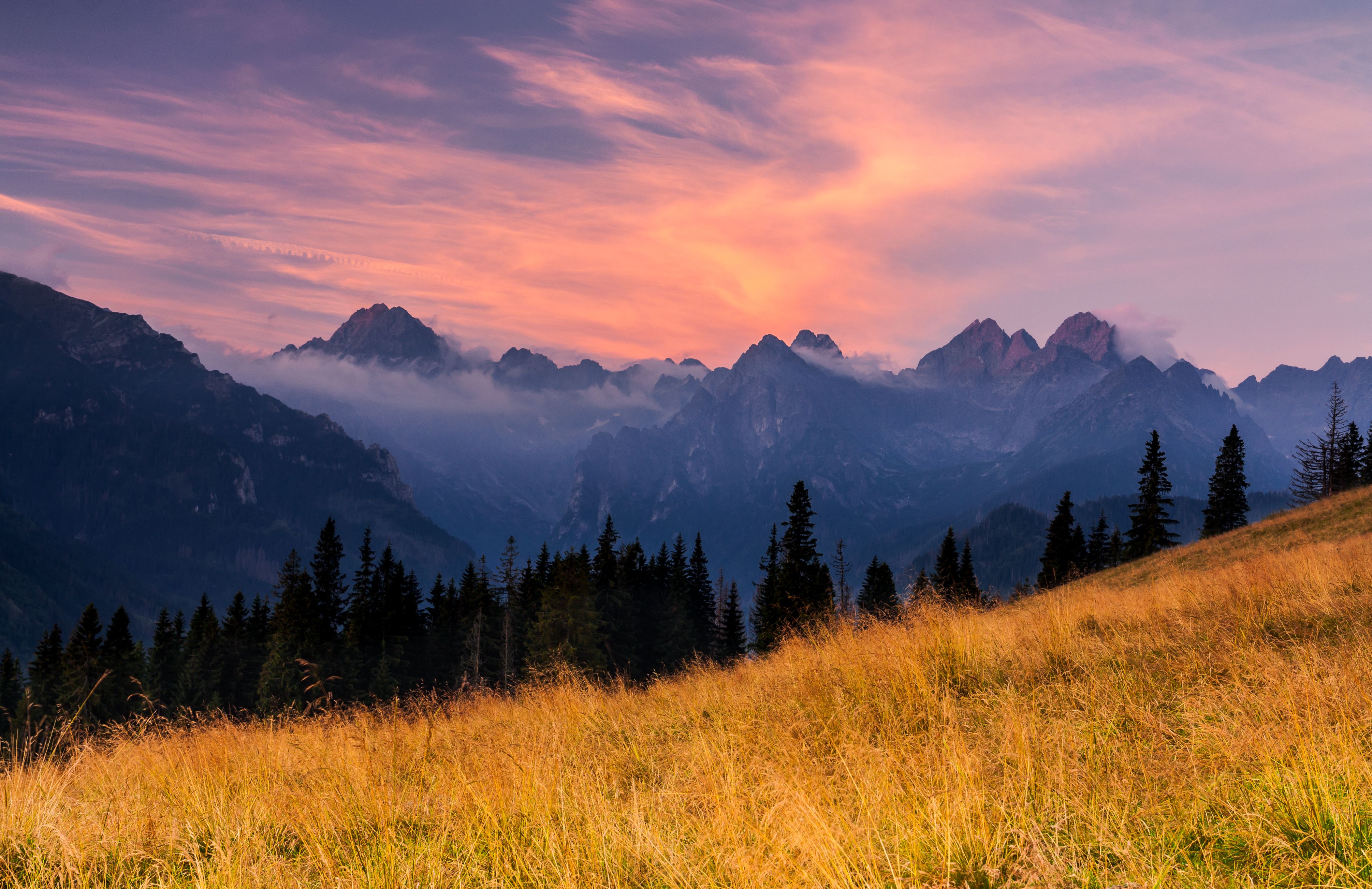 Beautiful sunset over the Tatra Mountains with a view of misty peaks and colorful sky.