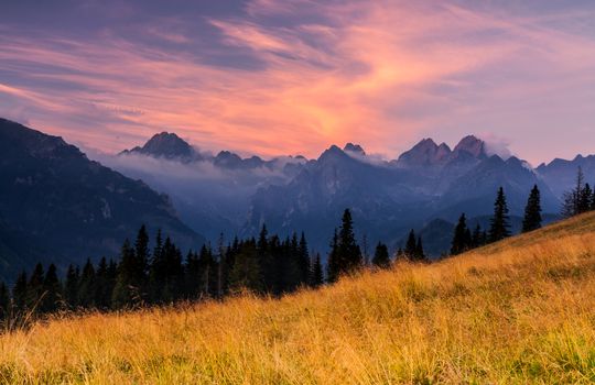 Beautiful sunset over the Tatra Mountains with a view of misty peaks and colorful sky.