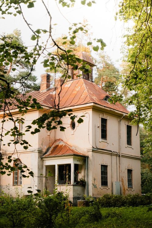 Free A picturesque vintage house with a red roof amidst lush greenery, creating a serene and idyllic scene. Stock Photo