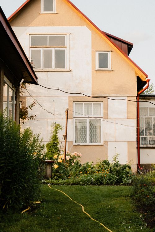 Free A quaint rural cottage surrounded by a vibrant garden, captured in warm summer light. Stock Photo