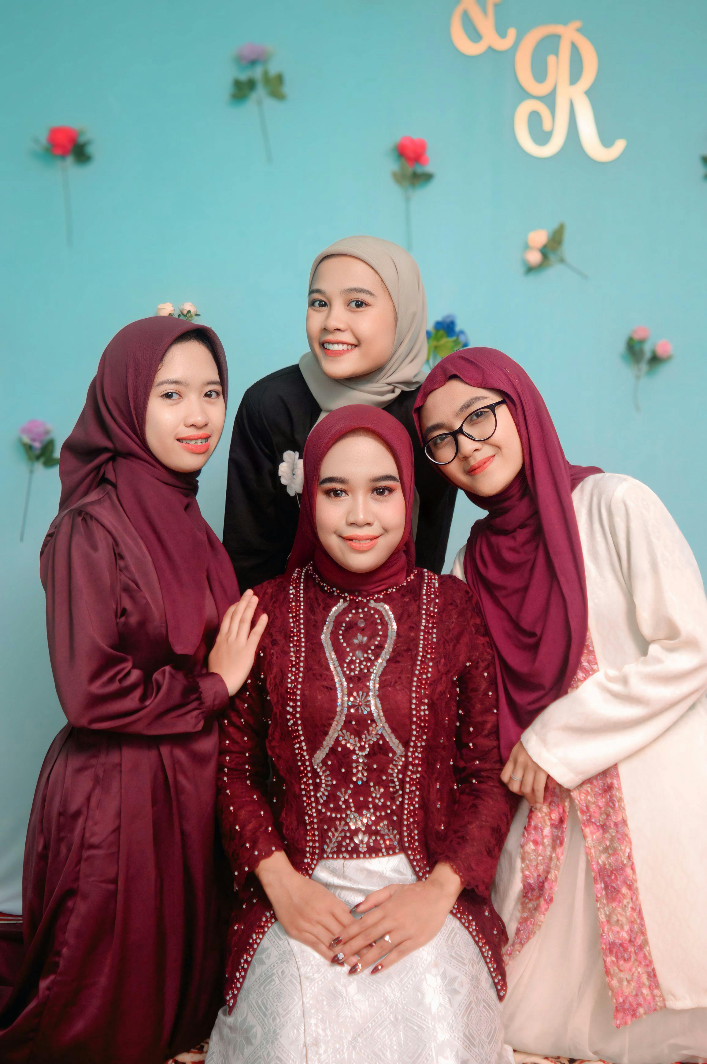 Gratuit Un charmant portrait de quatre femmes en tenue traditionnelle, posant chaleureusement sur un fond floral. Photos