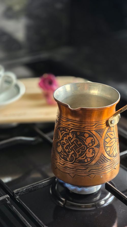 Free Beautifully engraved copper coffee pot on a stove, showcasing traditional design. Stock Photo
