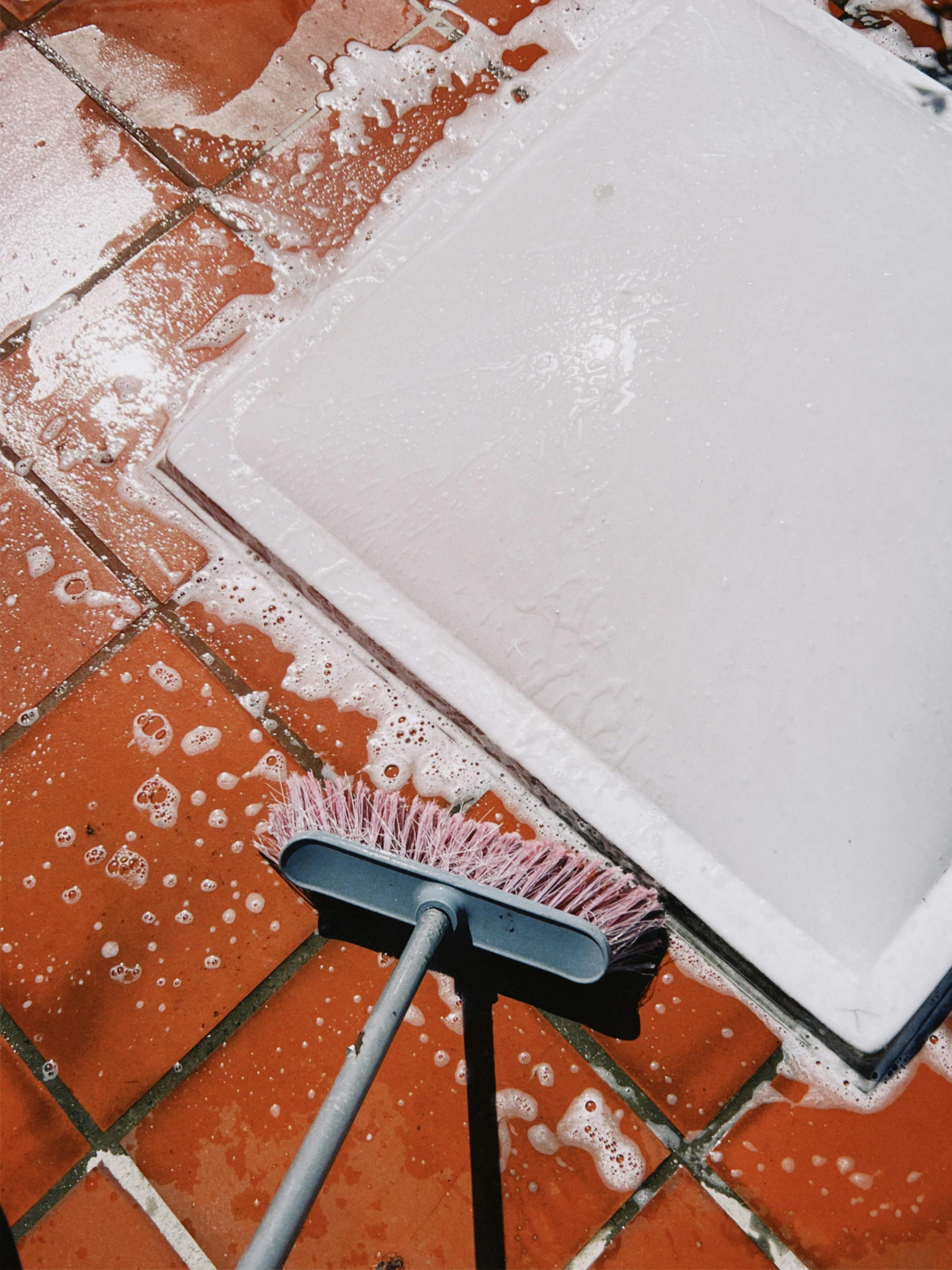 Spazzola e sapone usati per pulire piastrelle bagnate