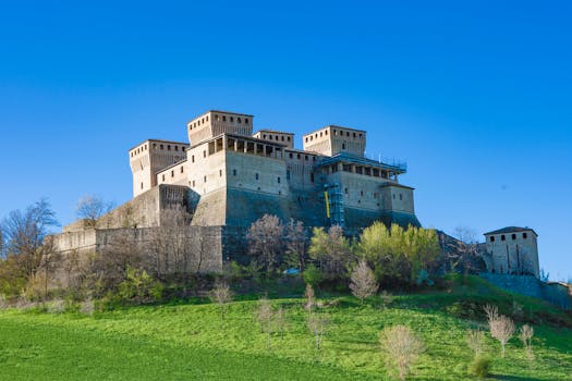 A stunning medieval castle set against a clear blue sky and lush green landscape.