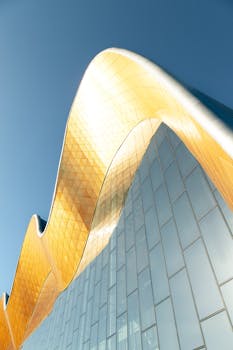 Striking modern architecture in Moscow, featuring golden wave-like structures against a clear sky.